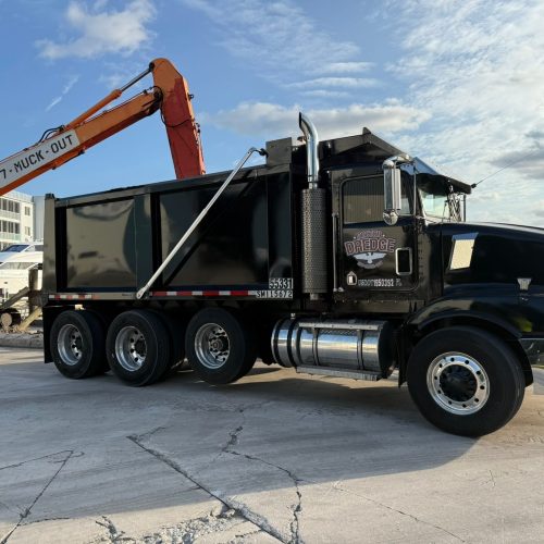 A serene landscape with a calm lake reflecting the surrounding forest and distant mountains under a clear blue sky.