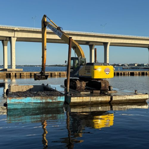 A serene beach scene with gentle waves lapping against the shore under a clear blue sky. Sparse clouds add depth to the horiz