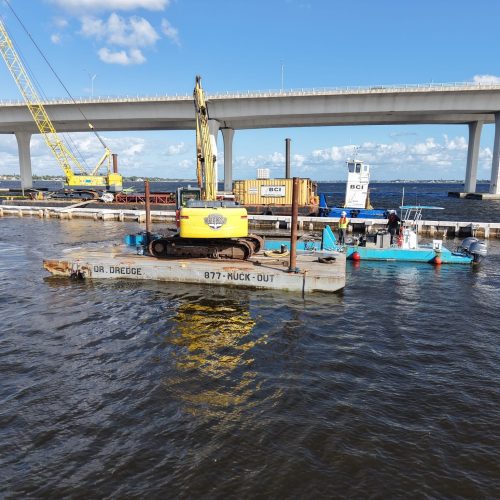 Aerial view of a coastal landscape with clear blue waters, sandy beaches, and lush greenery under a bright sky.